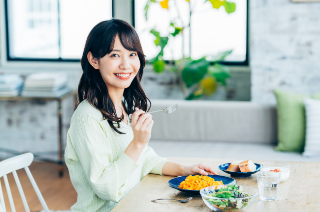 ワイヤー矯正で綺麗になった歯で食事を楽しむ女性